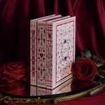 a set of three romantic pink style journals sitting on top of a mirror with a draped satin red background, surrounded by roses