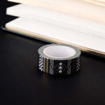 Roll of black washi tape with white flowers and leaves and gold foil