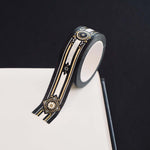 Black washi tape with white, grey and gold  flowers, a white band and gold foil filagree