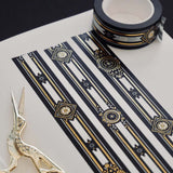 Black washi tape with white, grey and gold flowers, a white band and gold foil filagree