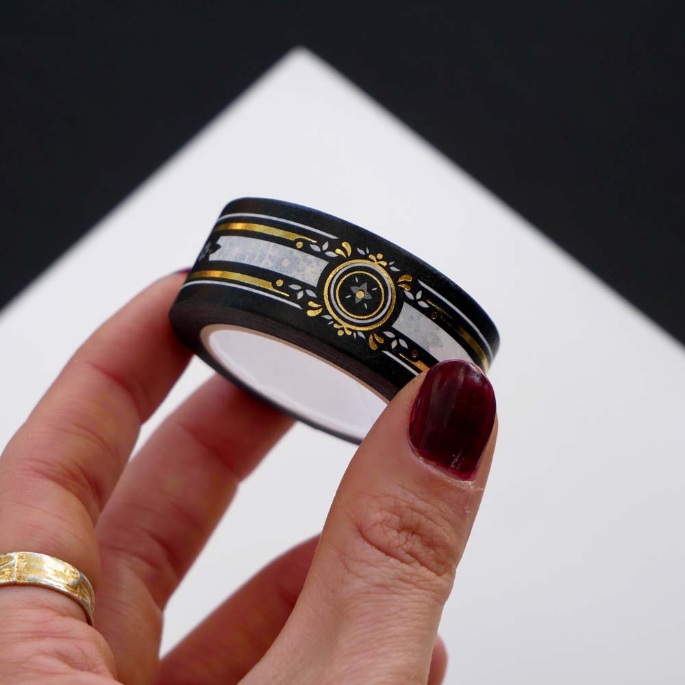 Black washi tape with white, grey and gold flowers, a white band and gold foil filagree