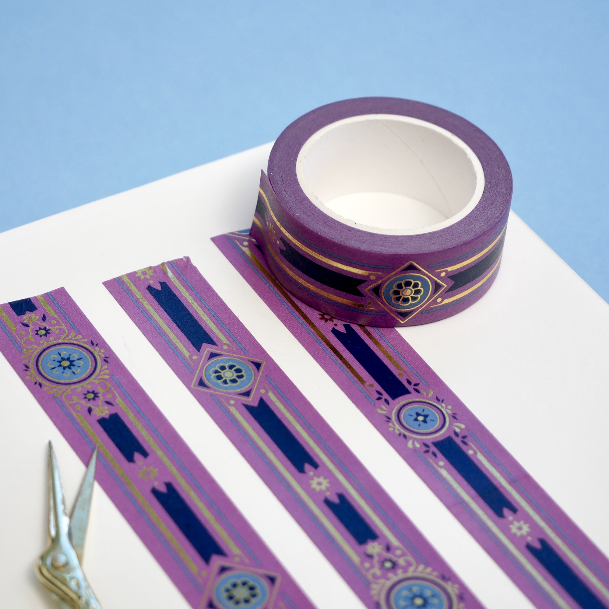 Purple washi tape with blue and gold flowers, a blue band and gold foil filagree