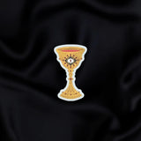 Blood Spilled- a fantasy vinyl sticker by The Quirky Cup Collective as part of the 'Serpents and Swords' collection- sits on a black fabric background. The book inspired sticker shows a goblet filled with blood with an eye motif on the front.