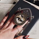 The Dragon Lore clingie by The Quirky Cup Collective is held by red nailed fingers as it is attached to a matching kindle sticker insert. The gold kindle grip features black,white and gold detailing and shows a dragon flying over clouds with a decorative border in a oval shape.