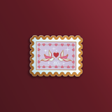 A bookish decorative sticker designed to resemble a postage stamp with a heart and birds graphic, 80c featured prominently in the center sits on a red background.