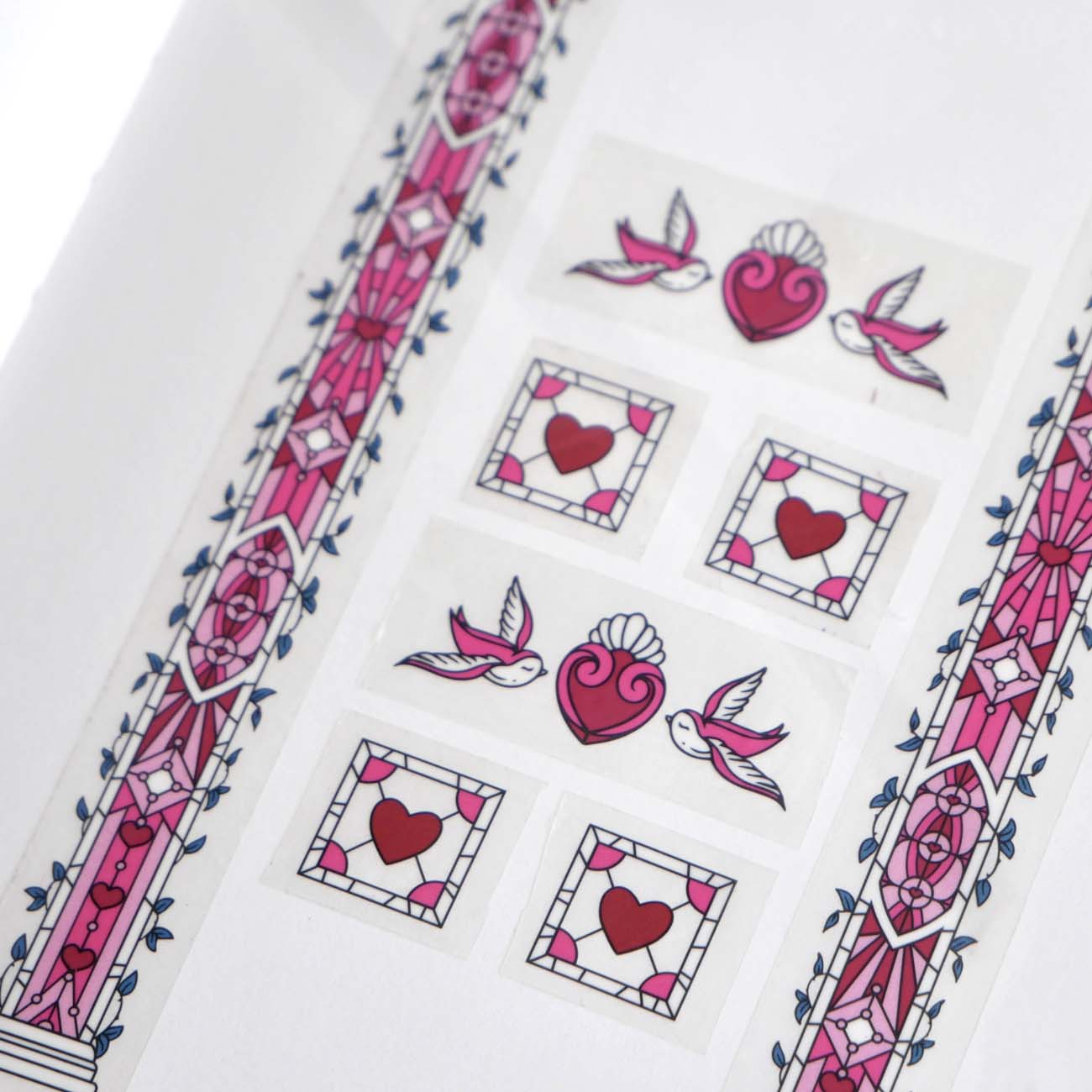 Clear washi tape with a pink panels, hearts and birds, and green foliage