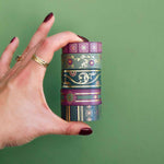 Five rolls of washi tape with green and purple backgrounds with flowers and gold foil
