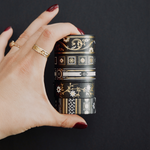 Five rolls of washi tape with a black background with white and gold flowers and gold foil