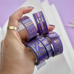 Five rolls of washi tape with a purple background with pink flowers and gold foil