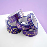 Five rolls of washi tape with a purple background with pink flowers and gold foil