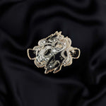 Black and silver hands with magic detailed enamel pin held by a hand against a dark background