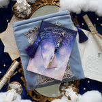 Bundle of stationery products sitting on whimsical celestial inspired background. Items include a blue celestial inspired bookmark, pen, journal and book sleeve.