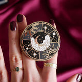 Hand holding a decorative kindle grip with celestial design against a pink fabric background