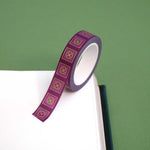 Roll of purple washi tape with green and purple flowers in pink squares outlined in gold foil