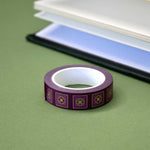 Roll of purple washi tape with green and purple flowers in pink squares outlined in gold foil