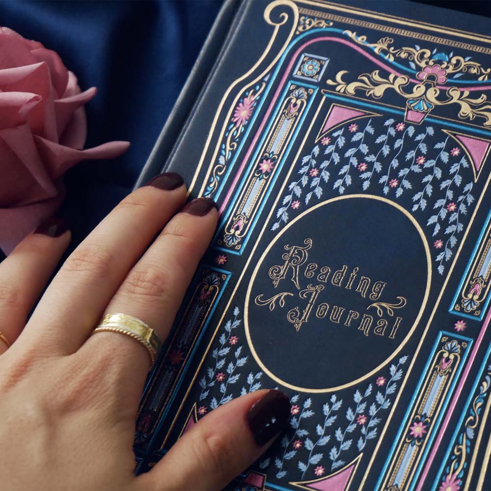 Blue faux leather reading journal with pink flowers, light blue leaves and gold foil filagree