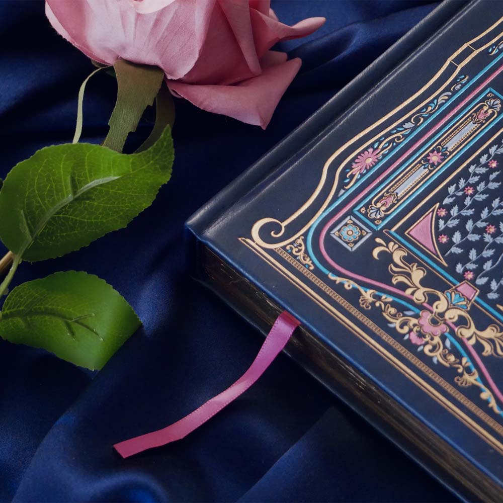 Blue faux leather reading journal with pink flowers, light blue leaves and gold foil filagree, and a pink ribbon bookmark