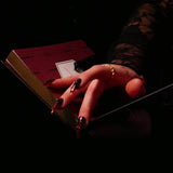 A promo image for the Serpents & Swords collection, a hand with long red nails rests their hand on an The Quirky Cup Collective journal in a dark setting.