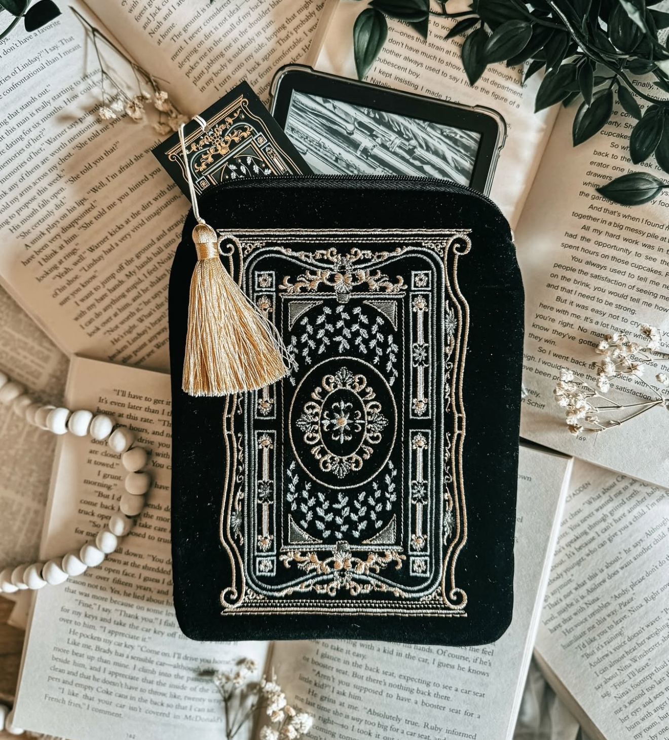 Decorative black e-reader case with tassel on an open book background