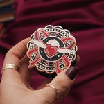 Heart with wings E-reader and phone grip held by a hand with dark nail polish against a black background