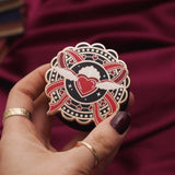 Heart with wings E-reader and phone grip held by a hand with dark nail polish against a black background