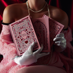 a set of three journals being suggsestively held with gloved hands. Journals are pink and romantic
