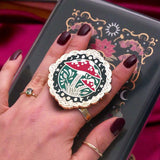 Decorative kindle grip with cottage core design held by a hand against a decorative background