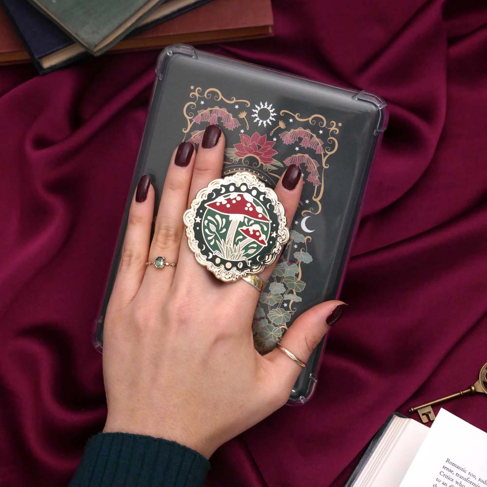 Decorative kindle grip with cottage core design held by a hand against a decorative background
