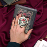 Decorative kindle grip with cottage core design held by a hand against a decorative background