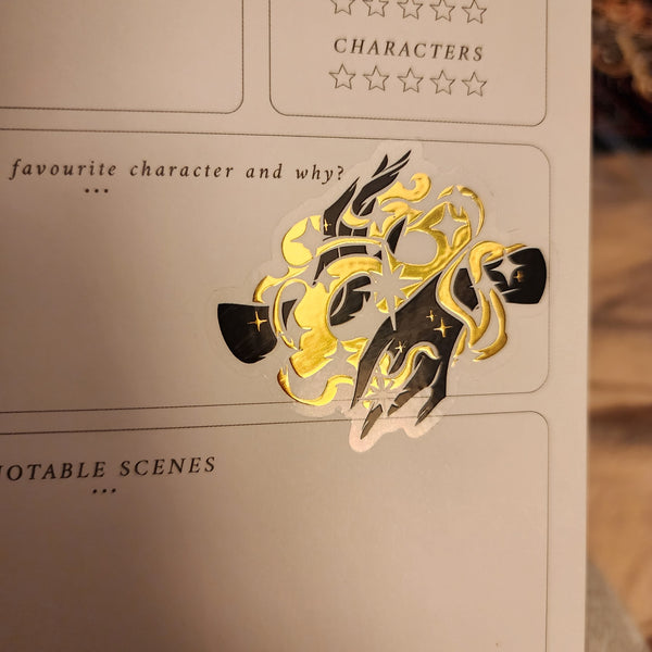A shiny magical sticker of hands stuck into a reading journal