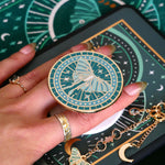 teal clingie depicting a luna moth featuring celestial accents positioned on the back of a kindle and accessories by the quirky cup collective