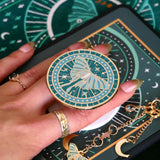teal clingie depicting a luna moth featuring celestial accents positioned on the back of a kindle and accessories by the quirky cup collective
