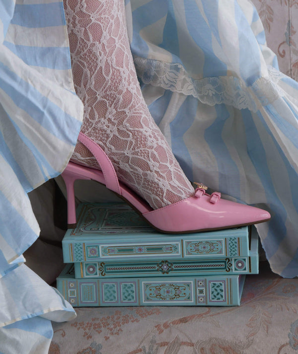 A campaign image for the Antoinette foil journal launch. A foot wearing lace stockings and pink heels stands on the stack of journals. The aqua journal, reading journal and reading companion feature intricate foiling in shades of pink, gold, cream and blue.