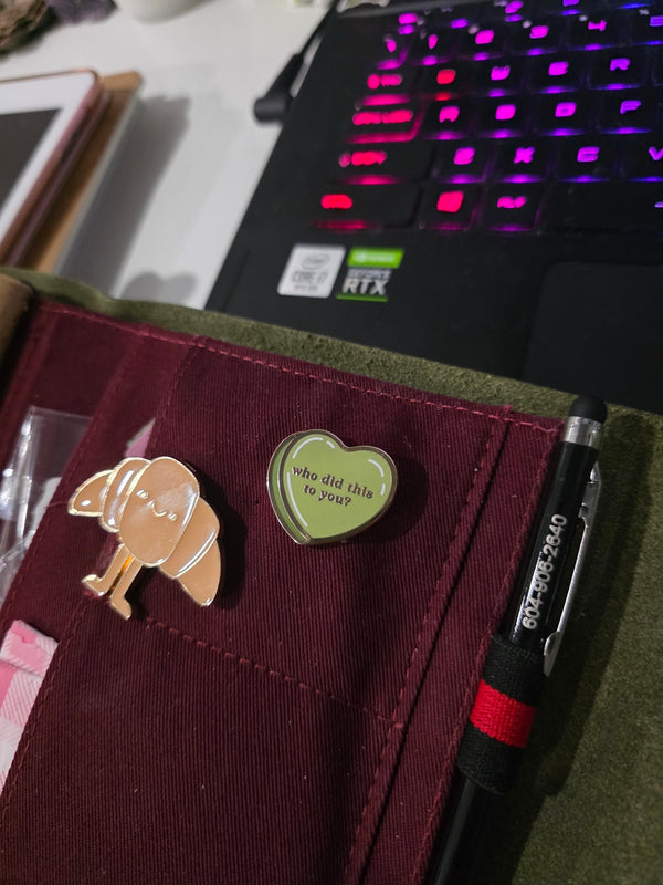 A Quirky enamel pin of a candy heart on a journal case.