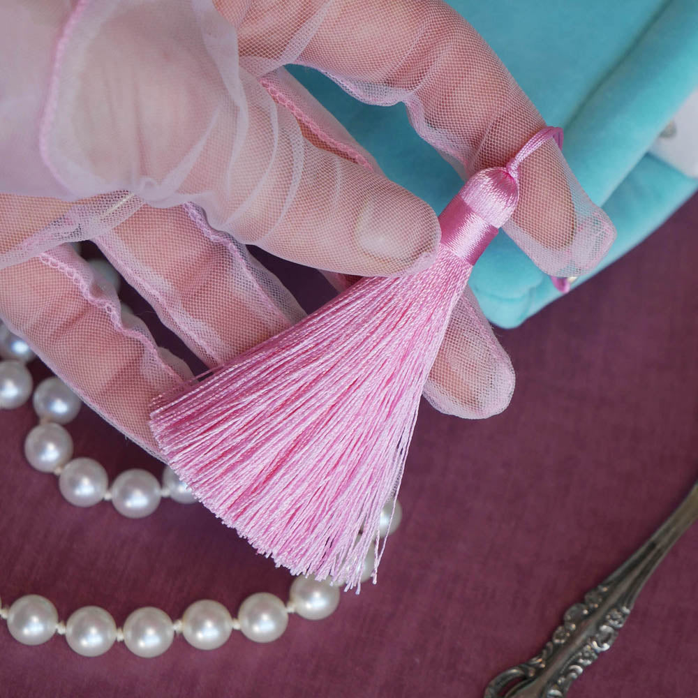 A detail of the mint green book sleeve Antoinette sits on a pink table. The pastel pink tassel i shown here, the perfect detail for a colourful classical book aesthetic.