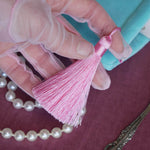 A detail of the mint green book sleeve Antoinette sits on a pink table. The pastel pink tassel i shown here, the perfect detail for a colourful classical book aesthetic.
