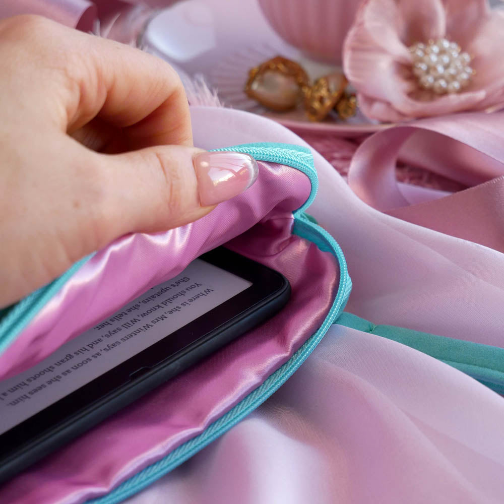 A detail of the aqua Kindle sleeve in Antoinette. The light green velvet Kobo case features pink, cream and gold embroidery with a classic book inspired design. Here a hand shows a eReader in the case, the pink satin interior showing.