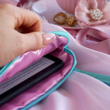 A detail of the aqua Kindle sleeve in Antoinette. The light green velvet Kobo case features pink, cream and gold embroidery with a classic book inspired design. Here a hand shows a eReader in the case, the pink satin interior showing.