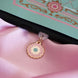 The Antionette dust plug design by The Quirky Cup Collective is plugged into a kindle on a light pink fabric background. The gold dust plug design (as part of the romantasy e-reader decor release) features a floral motif in shades of light pink, mint green and cream.