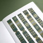 The Sage green variation of the Aurum Literati washi tape. The book inspired washi tape design is shown as 5 strips on a page of a journal on a green background and features a geometric design inspired by classical book ornaments in shades of dark green, sage green and gold.