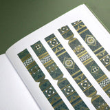 The Sage green variation of the Aurum Literati washi tape. The book inspired washi tape design is shown as 5 strips on a page of a journal on a green background and features a geometric design inspired by classical book ornaments in shades of dark green, sage green and gold.