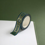 The Sage green variation of the Balteus Literati washi tape. The classic book inspired washi tape design is shown on the corner of a journal page on a green background and features a classic victorian motif with a small flower in shades of dark green, sage green, white and gold.