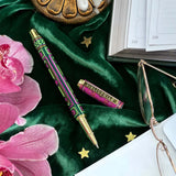 Decorative pen with pink flowers and a book on a green fabric background