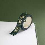 The Sage green variation of the Botanica Literati washi tape. The classic book inspired washi tape design is shown on the edge of a journal page on a green background and features a a vine covered in tiny flowers and leaves in shades of dark green, sage green, white and foiled gold.