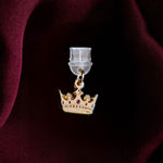 An detail shot of the gold Gilded Heir dust plug on a deep red fabric background. The fantasy aesthetic kindle decor sees the dust plug feature a small crown motif with red details.