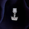 An detail shot of the silver Gilded Heir dust plug on a deep blue fabric background. The fantasy aesthetic kindle decor sees the dust plug feature a small crown motif with red details.