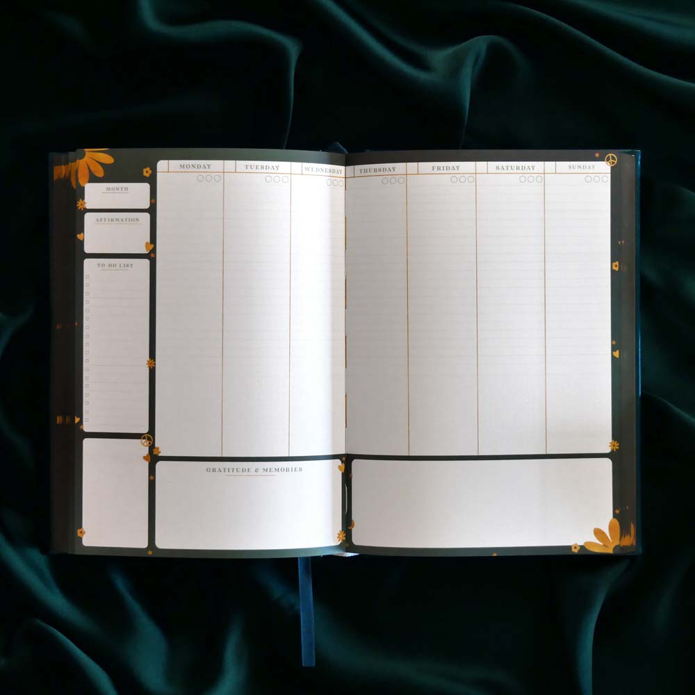 Open planner with gold accents on a dark green fabric background