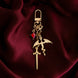 The gold Dragon rider Charmlet (A mix and match accessory for decorating your kindle) by The Quirky Cup Collective sits on a deep red fabric background. The design featured a gold clasp and multiple charms hanging from different length detachable chains including a dragon, a sword and a red gem.
