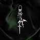 The silver Dragon rider Charmlet (A mix and match accessory for decorating your kindle) by The Quirky Cup Collective sits on a green background. The design featured a silver clasp and multiple charms hanging from different length detachable chains including a dragon, a sword and a green gem.