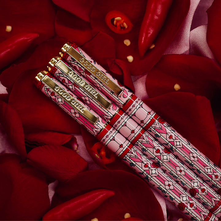 Good Girl - Pink Pen - Black Ink - The Quirky Cup Collective - Stained Glass Inspired Pen Design with 'Bite me' engraved on the pen clip. Pen sits on a bed of red rose petals. 